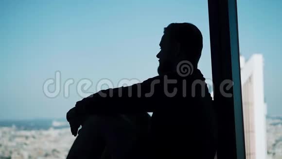 一个人坐在一个大的灯光窗户上的酷的轮廓凉爽厚重的气氛视频的预览图