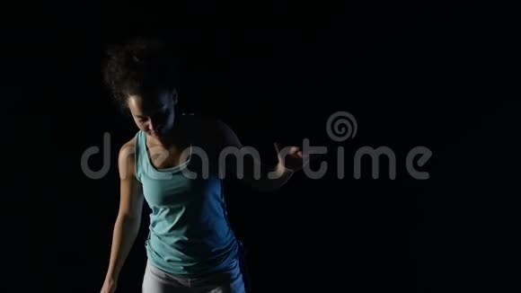 特写卷曲的女性在演播室黑暗中练习卡波伊拉慢动作视频的预览图