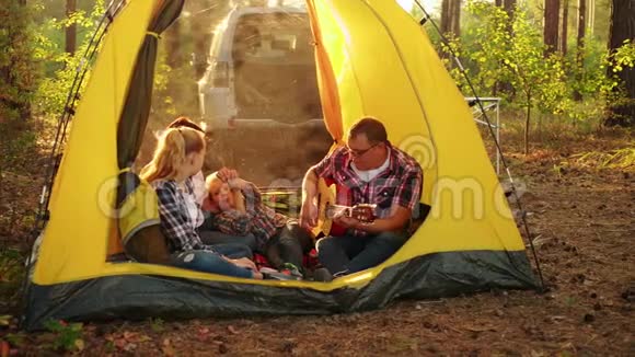 快乐的父亲在帐篷里给家人弹吉他视频的预览图