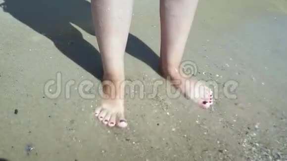海水冲刷着晒黑的雌性脚美丽的年轻女子在暑假期间在海岸放松视频的预览图