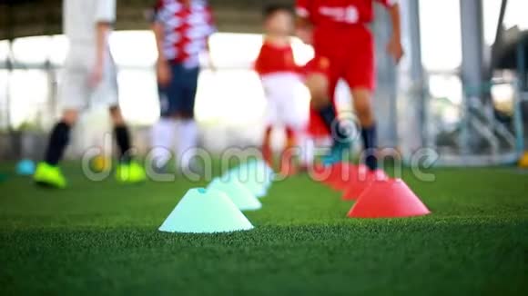 儿童足球运动员慢跑和跳之间的圆锥标志在绿色人造草坪上进行足球训练视频的预览图