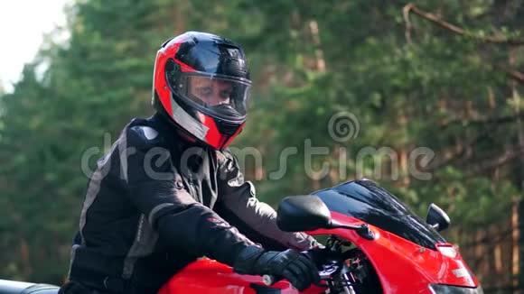 戴着头盔的男骑士坐在摩托车上看着摄像机视频的预览图