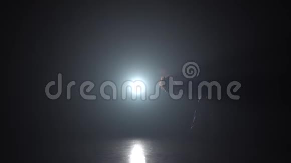 卡波伊拉由一名女子在黑暗工作室与前照灯表演慢动作视频的预览图