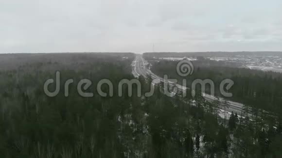 镜头飞向冬天的树林飞到公路的一侧视频的预览图