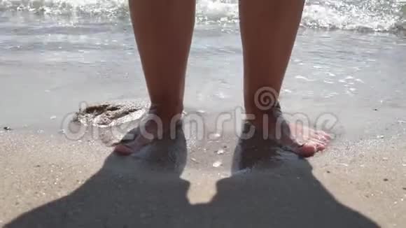海水冲刷着黝黑的雌性脚视频的预览图