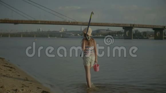 快乐的小女孩拿着鱼竿在水里行走视频的预览图