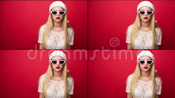 戴着圣诞老人帽子戴着墨镜的迷人金发女郎红色的背景特写肖像停止运动视频的预览图