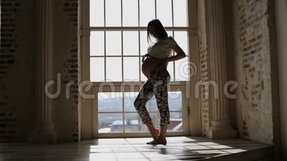 站在窗前侧影抚摸着肚子的孕妇视频的预览图