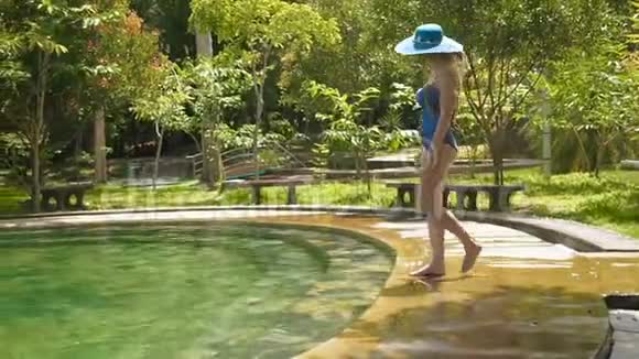 穿着蓝色泳衣帽子和太阳镜的性感女孩进入台阶上的热池慢动作小姐视频的预览图
