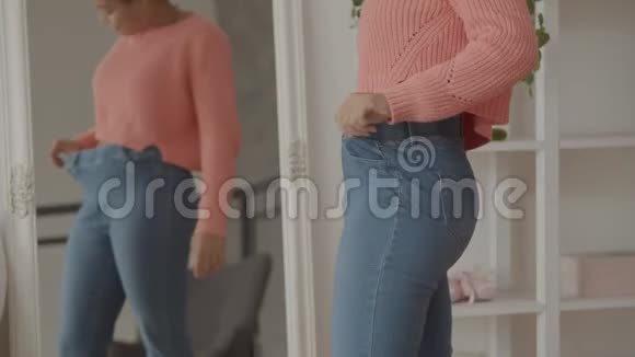 减肥后穿宽松旧牛仔裤的快乐女人视频的预览图
