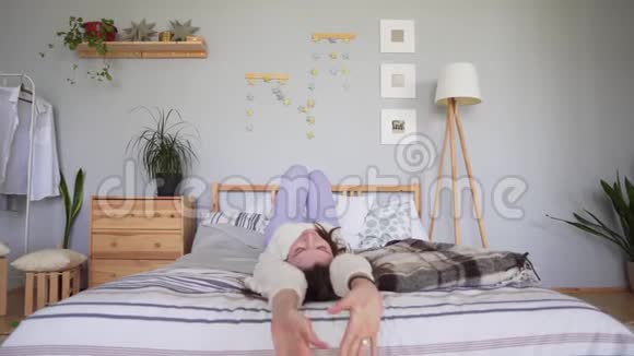 静态拍摄一个美丽迷人的女人穿着一件白色针织毛衣躺在舒适的床上倒置并使她挺直视频的预览图