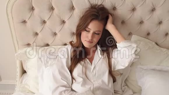 一位年轻女子的肖像早上在床上留着红色长发视频的预览图