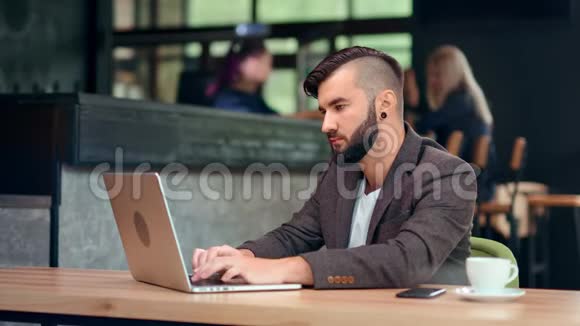 帅哥时髦的男商人用电脑上网聊天坐在咖啡馆的桌子上视频的预览图