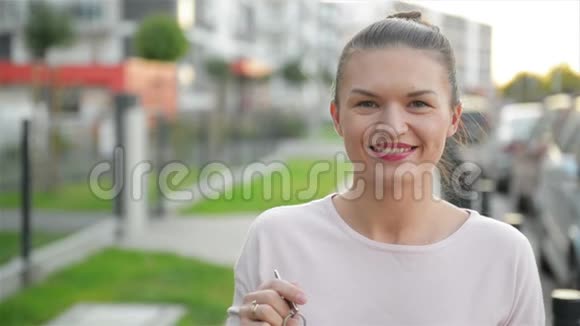 美丽的白种人女人拿着钥匙住在她的新房子附近视频的预览图