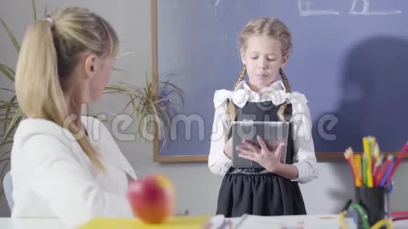 穿着校服的白种人女孩向坐在餐桌旁的中年教师炫耀的肖像视频的预览图