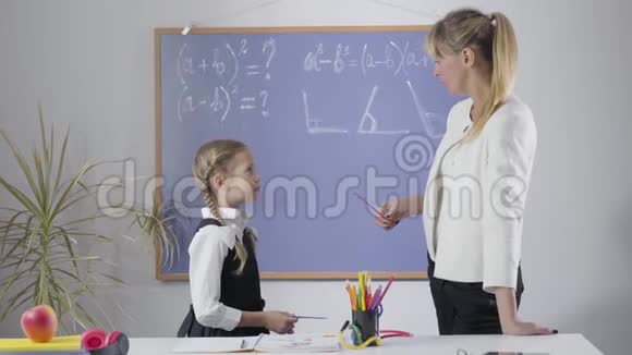穿着优雅校服的漂亮白种人女孩和中年家教站在黑板前学习的画像视频的预览图