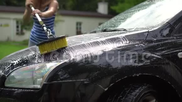 女工人用长毛刷和洗发水泡沫清洗汽车罩视频的预览图