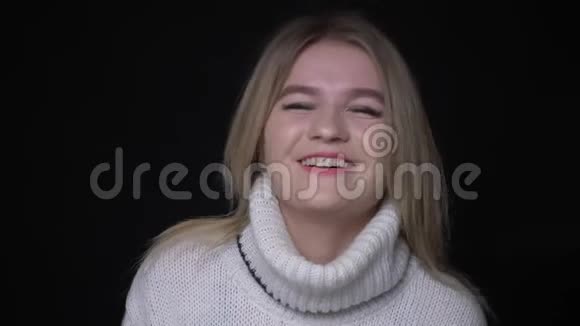 穿着毛衣的年轻漂亮白种人女性的特写镜头笑着开心地看着背景的镜头视频的预览图