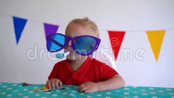可爱的男孩戴着巨大的眼镜在生日桌旁举行派对万向节运动视频的预览图