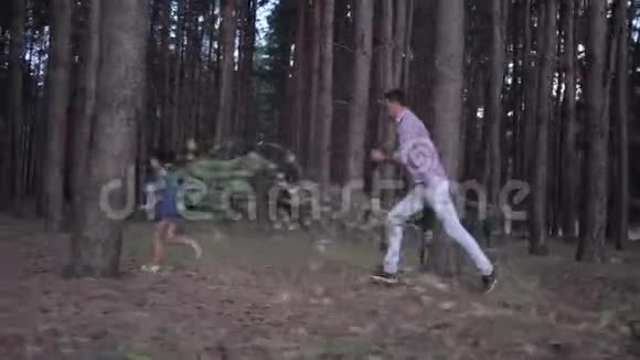 家庭关系愉快爸爸在假日期间在森林里的一排排大树之间玩耍追赶小女儿视频的预览图
