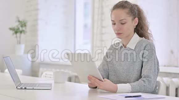 年轻的拉丁女人在办公室里用平板电脑视频的预览图