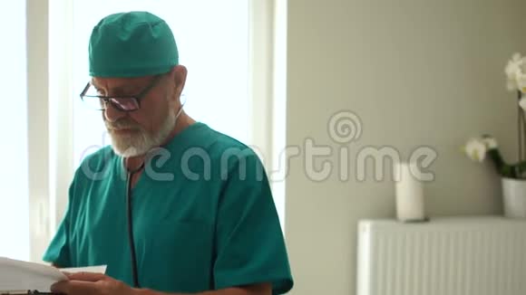 成熟的男性医生留着灰色的胡须和眼镜看着病人病史国际医生日视频的预览图