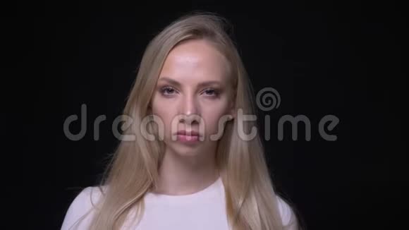 年轻漂亮的金发女性的特写镜头悲伤愤怒地看着背景与黑色隔离的镜头视频的预览图