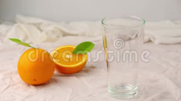 在白色背景下将橙汁从水壶倒入玻璃杯中视频的预览图