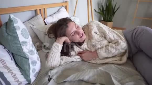 漂亮漂亮的漂亮女人睡在一张有很多枕头的舒适的床上寻找一个舒适的睡眠位置视频的预览图
