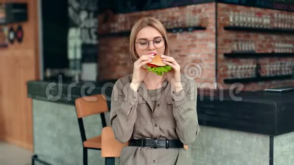 饥肠辘辘的休闲美女在餐馆里摆着开胃菜的汉堡情绪激动视频的预览图