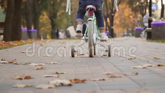 小女孩骑自行车在秋城大道后景视频的预览图