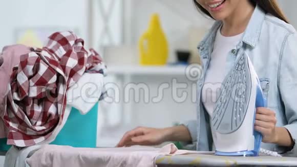 心情愉快的家庭主妇喜欢熨烫t恤享受家务劳动特写视频的预览图