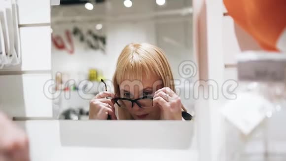 商店里镜子前戴眼镜的女孩时尚有趣的框架视频的预览图