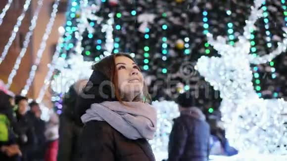 美丽的年轻女子看着雪夜晚的城市装饰圣诞节和新年视频的预览图