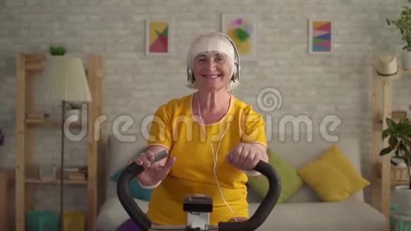 积极健身的老年妇女在运动自行车上做运动时会露出大拇指和微笑视频的预览图