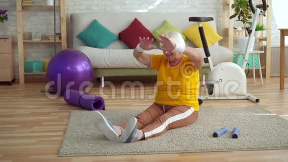 积极向上的老年妇女在客厅的地毯上做热身运动视频的预览图
