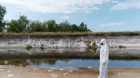 穿着防护服和呼吸器的人站在塑料垃圾桶中靠近一条干涸的河流打开摄像机视频的预览图