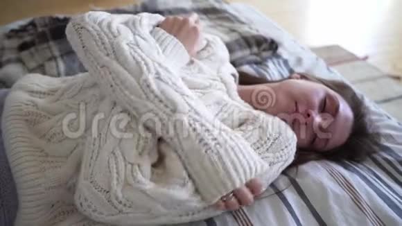时尚概念一个美丽的女孩沐浴在舒适的米色毛衣和享受舒适的家视频的预览图