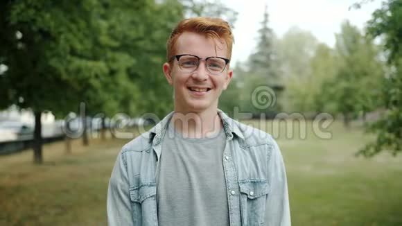 夏天在城市公园里戴眼镜的红发帅哥慢动作视频的预览图