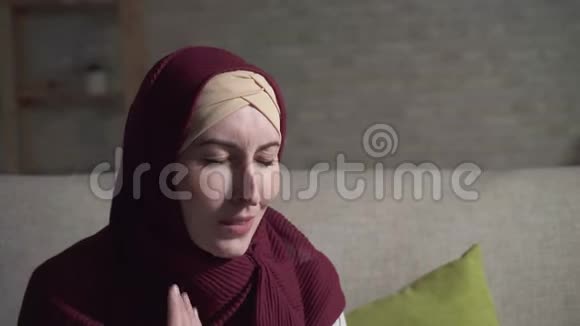 忧郁症的年轻穆斯林女人坐在客厅里的沙发上哭得紧紧的视频的预览图