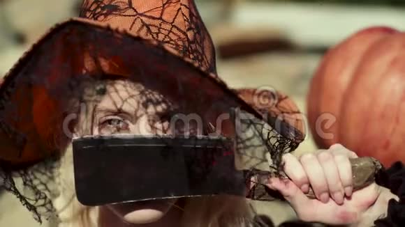 美丽的年轻惊讶的女人戴着巫婆帽和万圣节服装有趣的万圣节脸假日装饰和视频的预览图