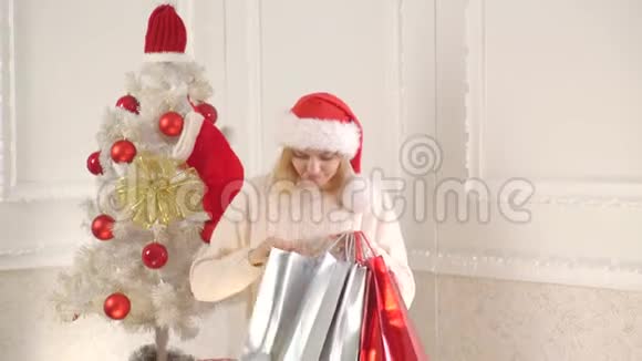 很漂亮的圣诞老人圣诞节购物包和购物她穿着圣诞礼服新年促销和圣诞节折扣视频的预览图