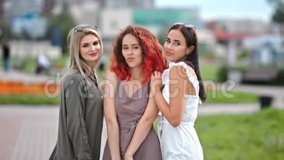 三位不同类型的年轻女朋友一起玩一起在户外摆姿势看摄像机视频的预览图