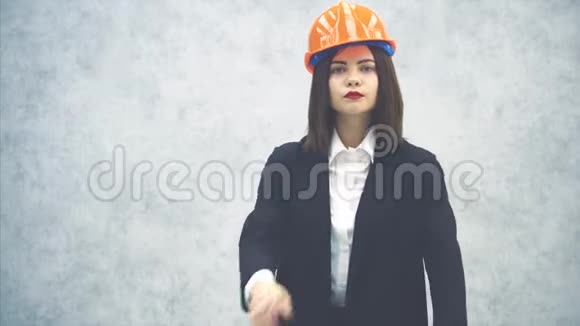 美丽的年轻女建筑师戴着头盔和西装看着相机摆姿势双手视频的预览图