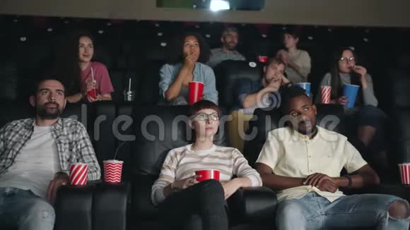 男人和女人在电影院里打哈欠喝酒看无聊电影的慢动作视频的预览图