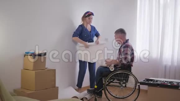 家庭维修心爱的残疾人坐在轮椅上年轻漂亮的妻子选择新卧室的壁纸视频的预览图
