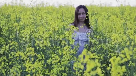 美丽的女孩跑在黄花里油菜地视频的预览图