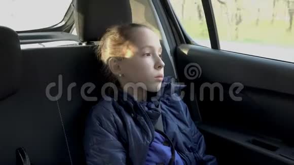一个悲伤的小女孩的肖像她从一辆驾驶汽车的窗户上沉思地看着日落她的脸视频的预览图