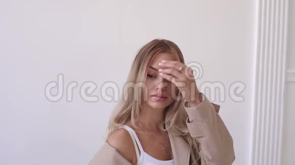 性感的女孩留着米色外套的长发在白色背景的工作室里视频的预览图
