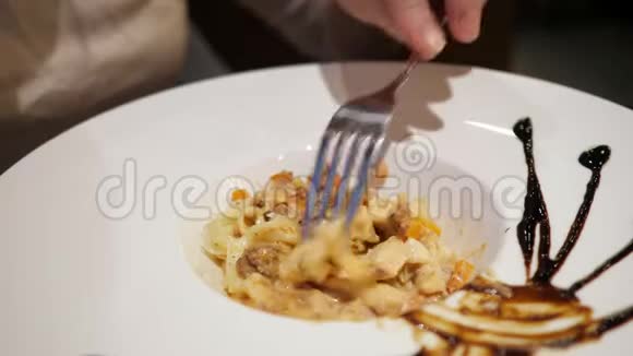 大盘子里的意大利面的特写女人用叉子的手视频的预览图
